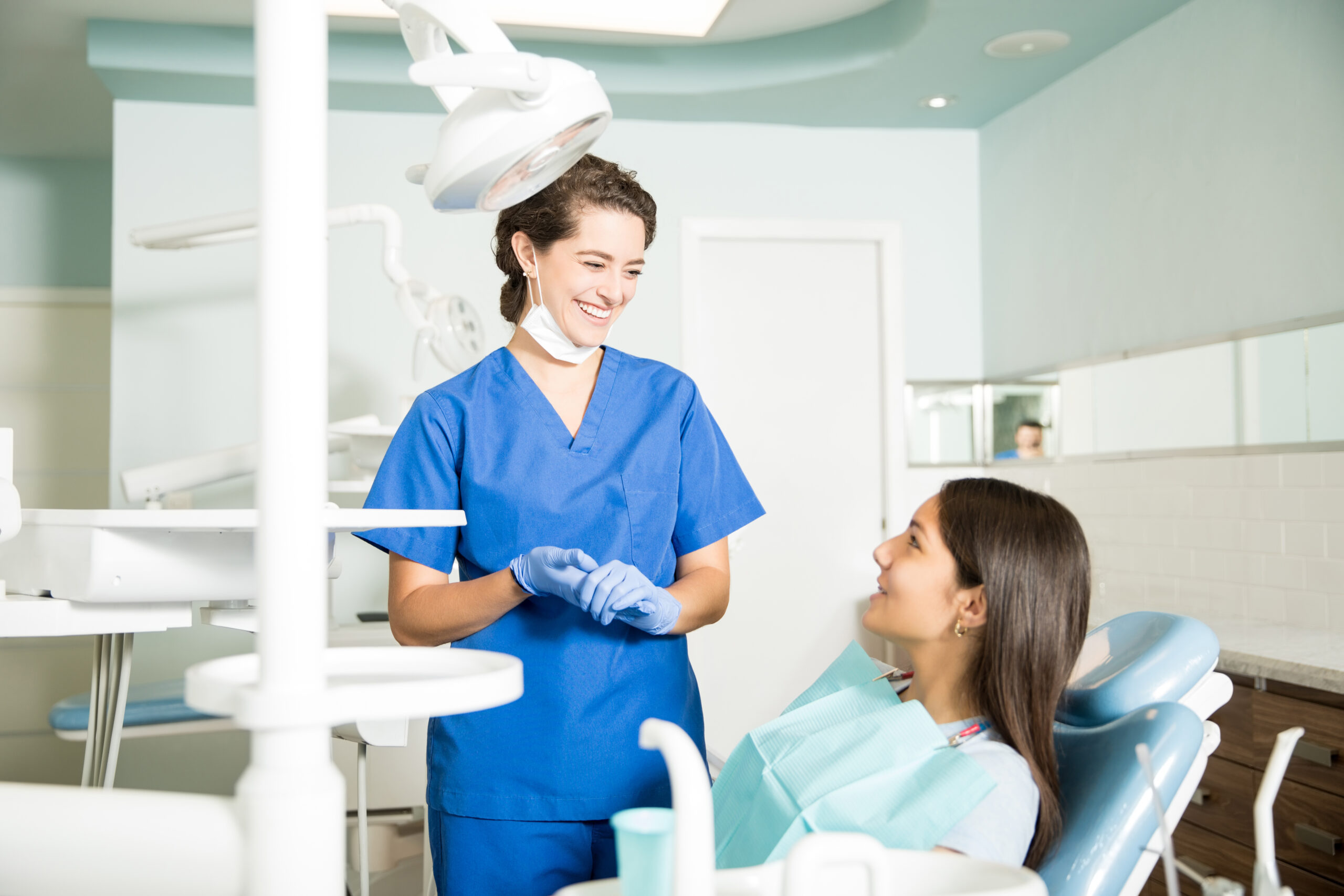 Assistente odontoiatrica e paziente sorridenti interagiscono in un moderno studio dentistico, simbolo di cura e competenza professionale.